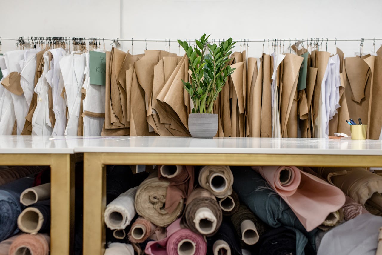 Interior of a fashion studio featuring fabric rolls and dress patterns on hangers.